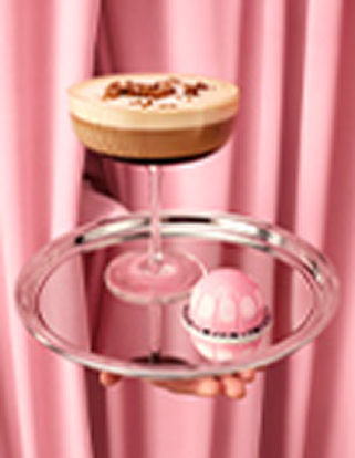 Coffee cocktail and pink capsule on a silver tray in front of pink curtains